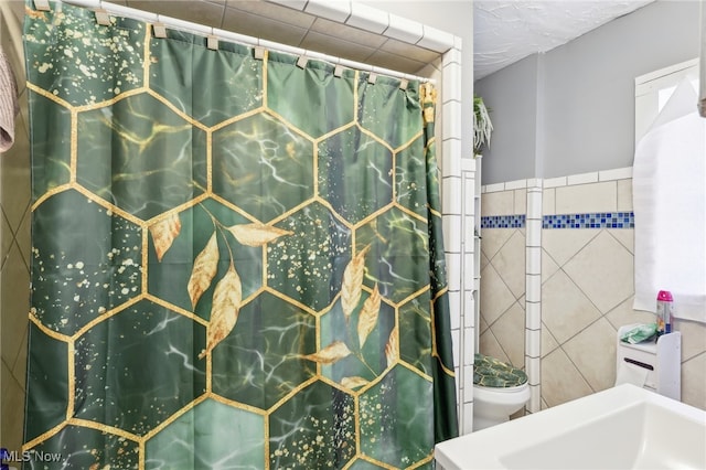 bathroom featuring tile walls and toilet