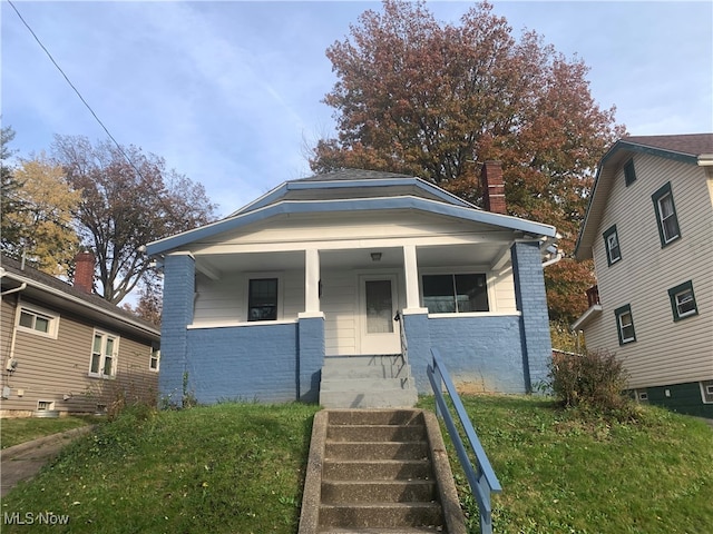 bungalow-style house with a front yard and covered porch