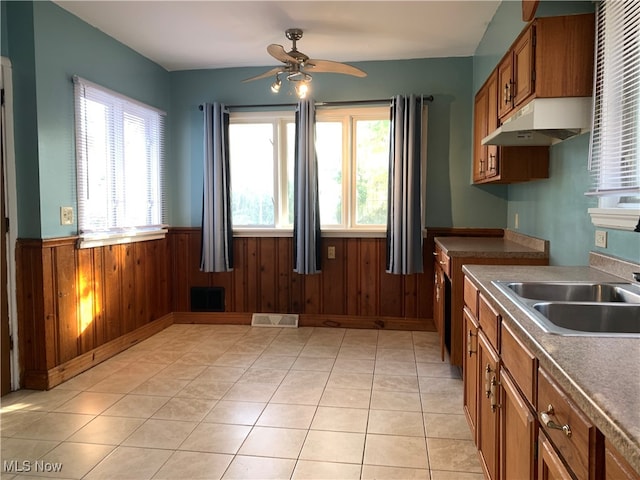 kitchen featuring wood walls, sink, light tile patterned floors, and ceiling fan