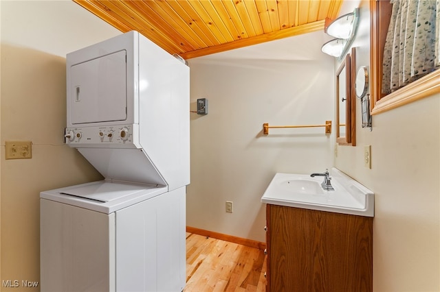 laundry area with sink, stacked washer and dryer, light wood-type flooring, and wooden ceiling