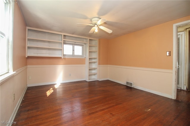 spare room featuring dark wood-type flooring, ceiling fan, and a healthy amount of sunlight