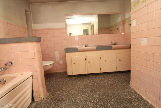 bathroom with vanity, toilet, tile walls, and a bathing tub