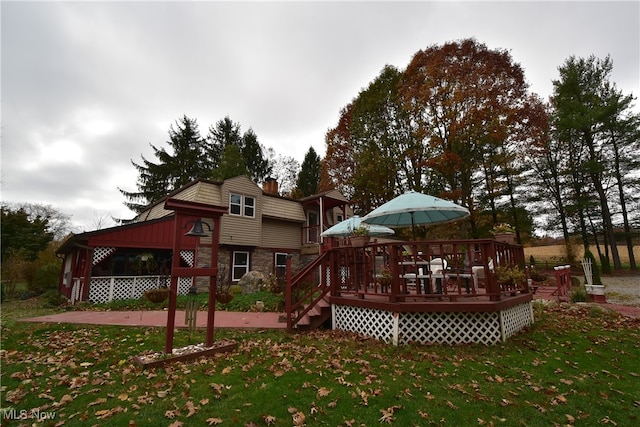 back of property featuring a deck and a lawn