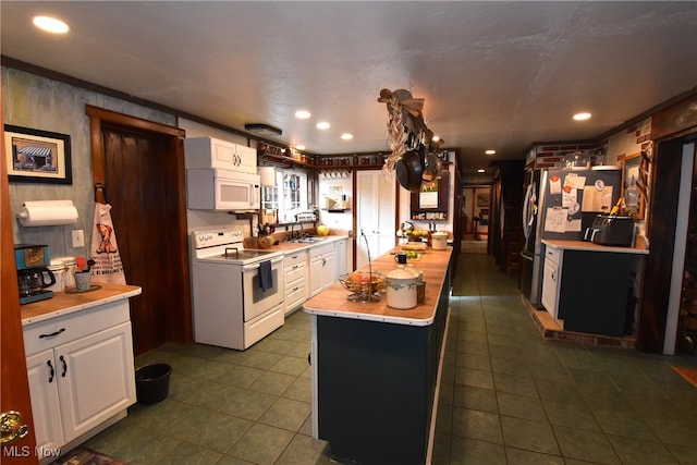 kitchen with white cabinets, sink, dark tile patterned floors, and white appliances