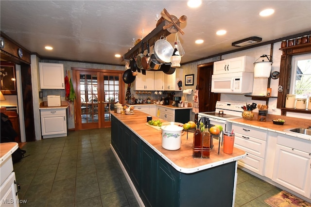 kitchen with white cabinets, hanging light fixtures, a center island with sink, french doors, and white appliances