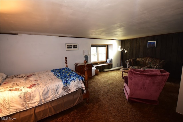 bedroom featuring wood walls and dark colored carpet