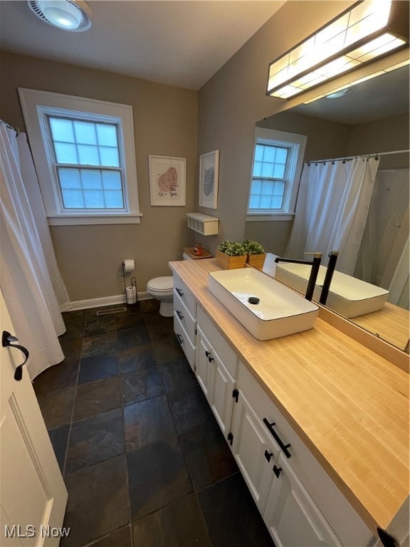 bathroom with plenty of natural light, vanity, and toilet