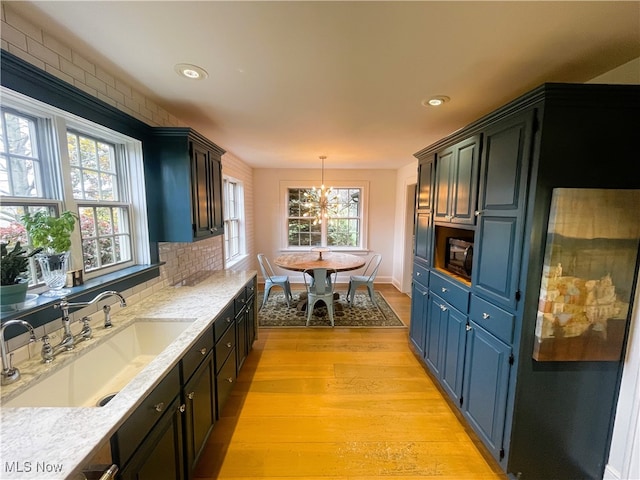 kitchen with pendant lighting, a healthy amount of sunlight, light hardwood / wood-style floors, and sink