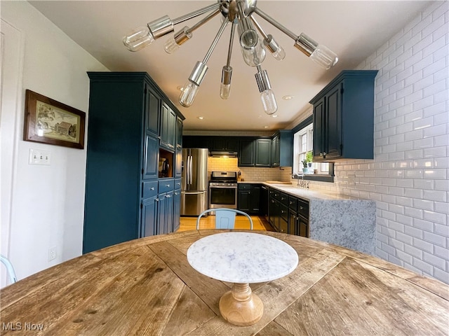 kitchen with tasteful backsplash, blue cabinetry, sink, and appliances with stainless steel finishes