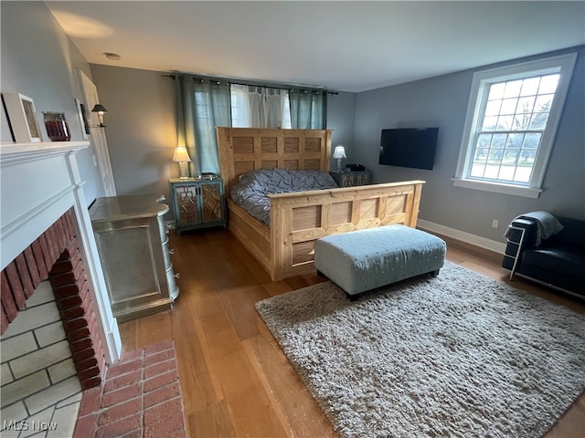 bedroom featuring wood-type flooring and a fireplace