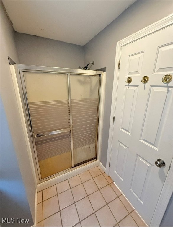 bathroom featuring a shower with shower door and tile patterned flooring