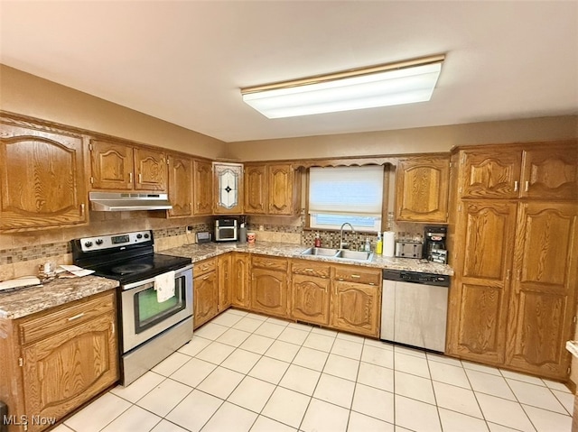 kitchen with sink, stainless steel appliances, backsplash, and light tile patterned floors