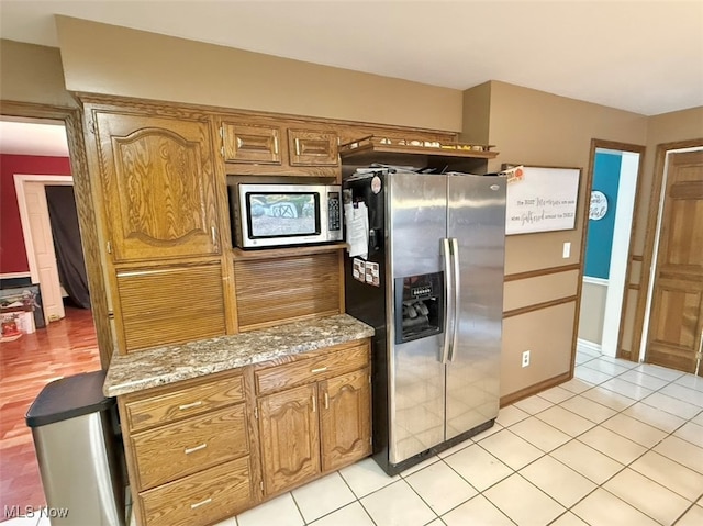 kitchen featuring light tile patterned flooring, light stone counters, and stainless steel fridge with ice dispenser