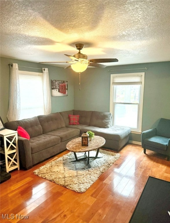 living room with hardwood / wood-style floors, a textured ceiling, and ceiling fan