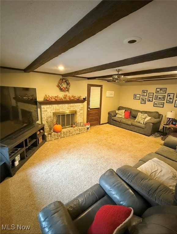 carpeted living room featuring ceiling fan, beamed ceiling, and a fireplace