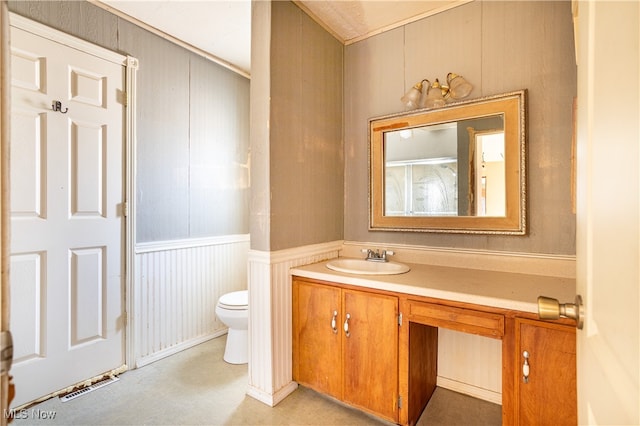 bathroom featuring toilet, wood walls, and vanity