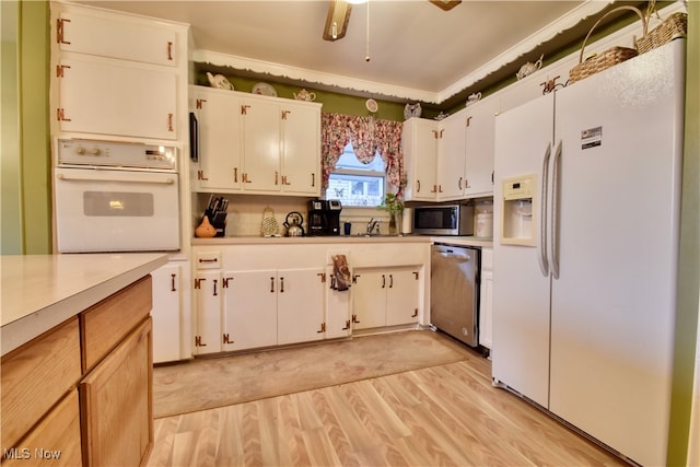 kitchen featuring appliances with stainless steel finishes, white cabinetry, light hardwood / wood-style flooring, and sink