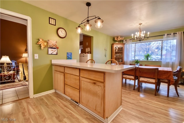 kitchen with kitchen peninsula, light brown cabinets, light hardwood / wood-style floors, and a notable chandelier