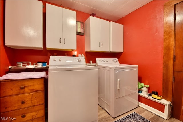 washroom featuring cabinets, light wood-type flooring, and washer and clothes dryer