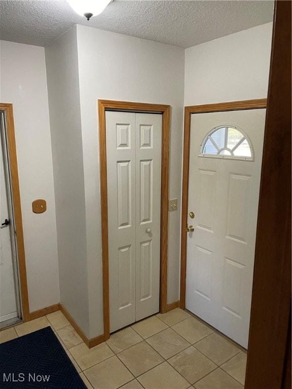 entryway with a textured ceiling and light tile patterned floors