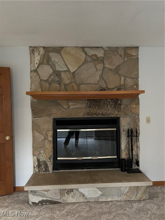 room details featuring a stone fireplace and carpet floors