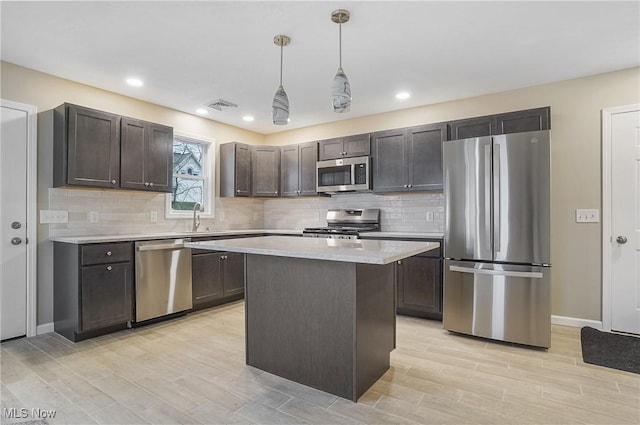 kitchen featuring a center island, sink, hanging light fixtures, appliances with stainless steel finishes, and dark brown cabinetry