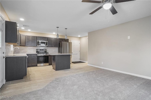 kitchen with stainless steel appliances, sink, pendant lighting, light hardwood / wood-style floors, and a kitchen island