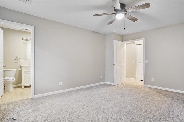 unfurnished bedroom with ceiling fan, light colored carpet, and ensuite bath