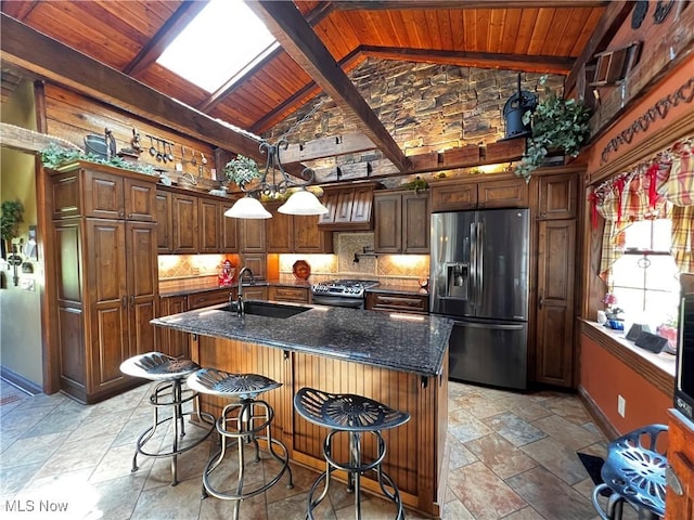 kitchen featuring vaulted ceiling with beams, a kitchen bar, sink, an island with sink, and stainless steel appliances