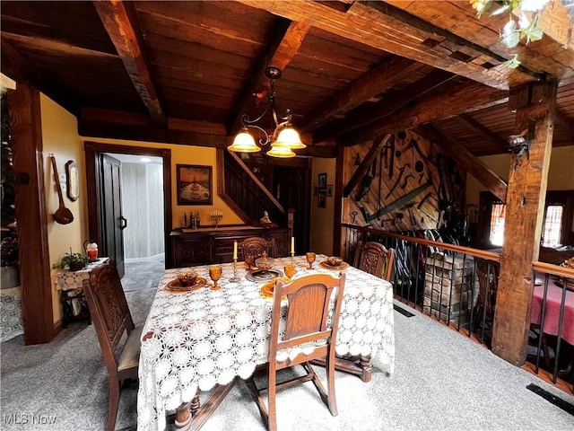 carpeted dining space with beamed ceiling, a chandelier, and wooden ceiling