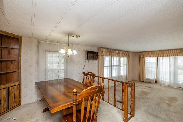 dining space featuring a wall unit AC, a textured ceiling, a notable chandelier, and light colored carpet