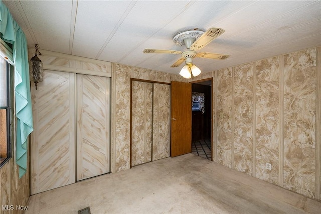 interior space featuring ceiling fan, wooden walls, multiple closets, and carpet floors