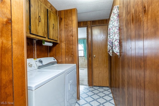 laundry area with wooden walls, separate washer and dryer, and cabinets