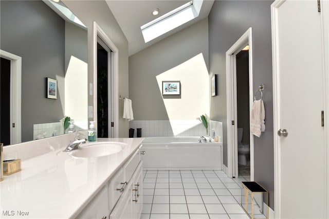 bathroom featuring a tub to relax in, toilet, vanity, lofted ceiling with skylight, and tile patterned flooring