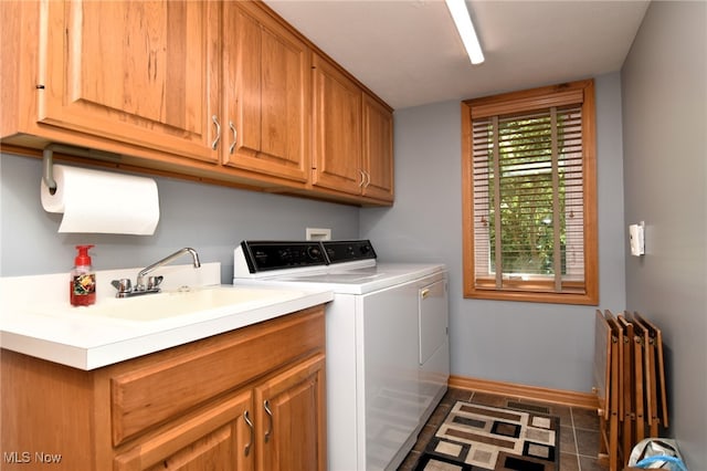 clothes washing area with sink, dark tile patterned flooring, separate washer and dryer, and cabinets