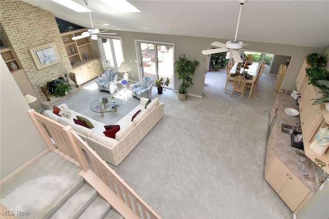 carpeted living room featuring ceiling fan, high vaulted ceiling, and a brick fireplace