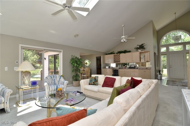 carpeted living room with ceiling fan, high vaulted ceiling, a skylight, and beverage cooler