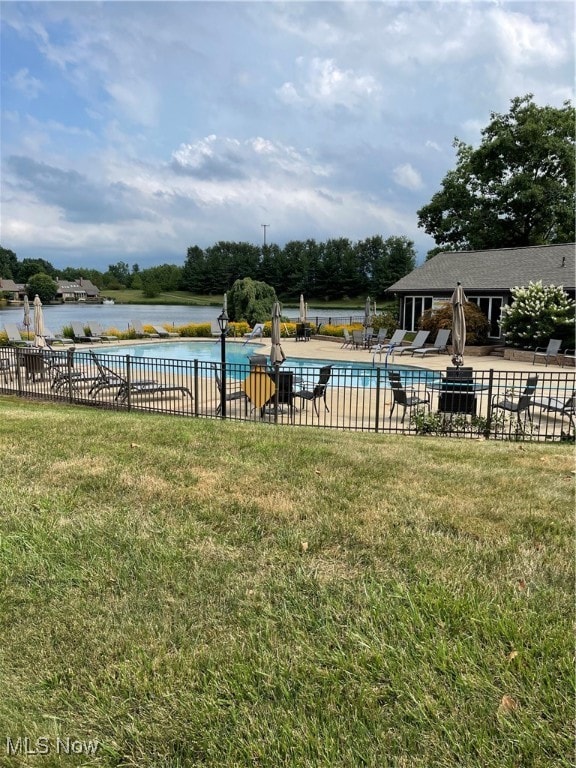 view of swimming pool with a water view, a patio area, and a lawn