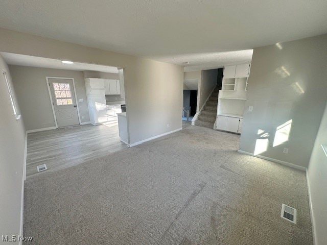 unfurnished living room featuring light colored carpet