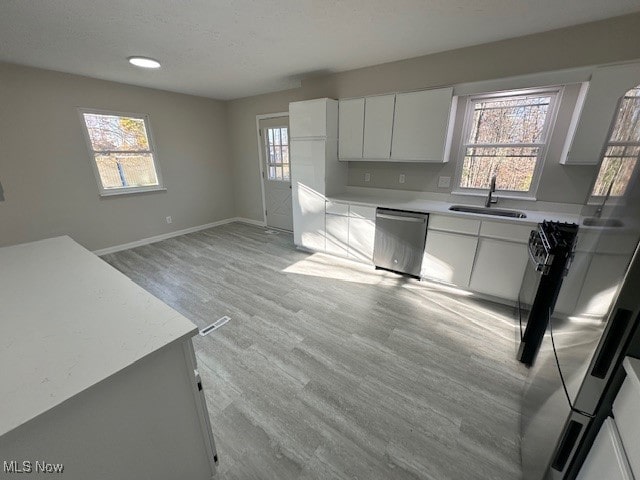 kitchen with white cabinets, stainless steel dishwasher, sink, and plenty of natural light