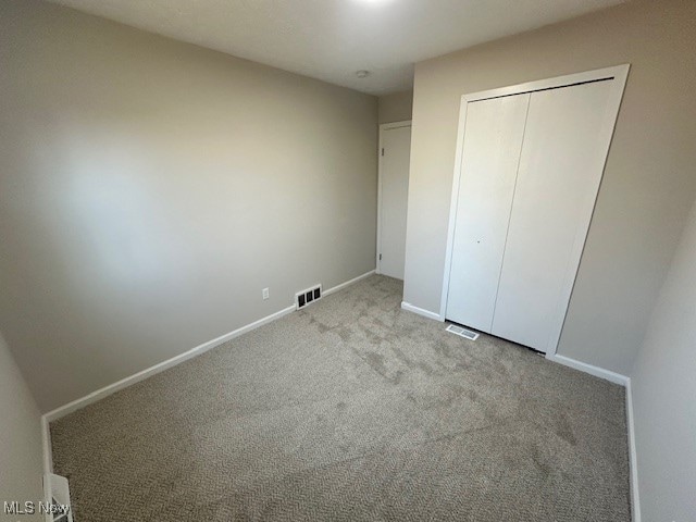 unfurnished bedroom featuring a closet and light carpet