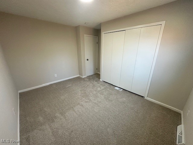 unfurnished bedroom featuring a closet, a textured ceiling, and carpet