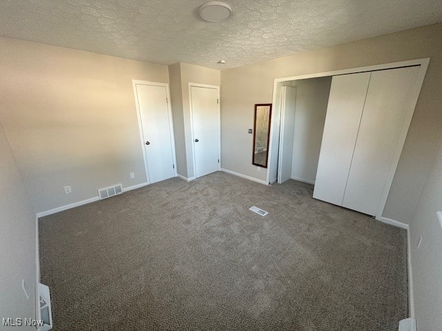 unfurnished bedroom featuring carpet, a textured ceiling, and a closet