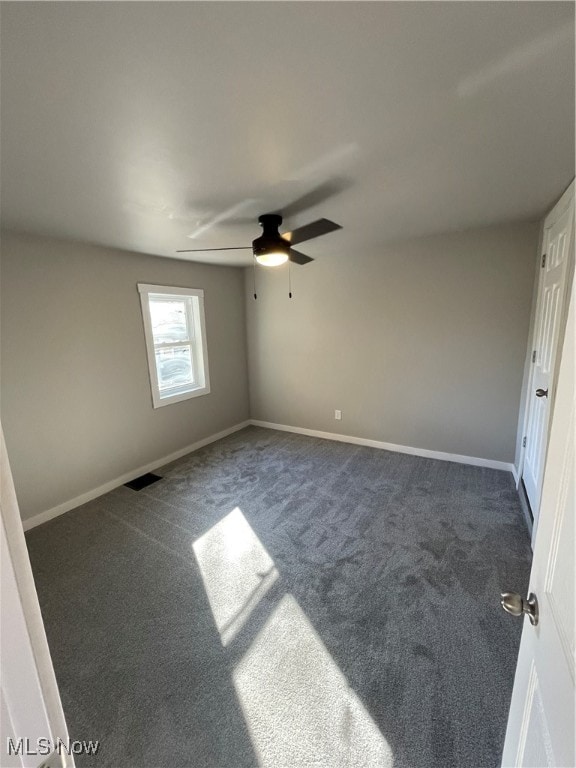 unfurnished room with dark carpet and ceiling fan