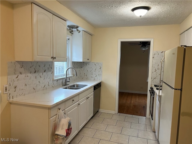 kitchen featuring decorative backsplash, a textured ceiling, white appliances, sink, and white cabinetry