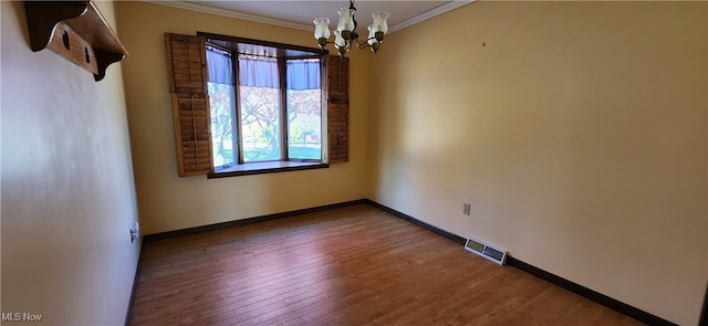 spare room with crown molding, a notable chandelier, and wood-type flooring