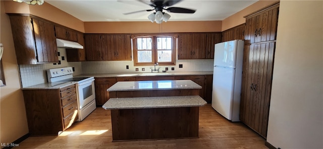 kitchen with white appliances, tasteful backsplash, sink, light wood-type flooring, and a kitchen island