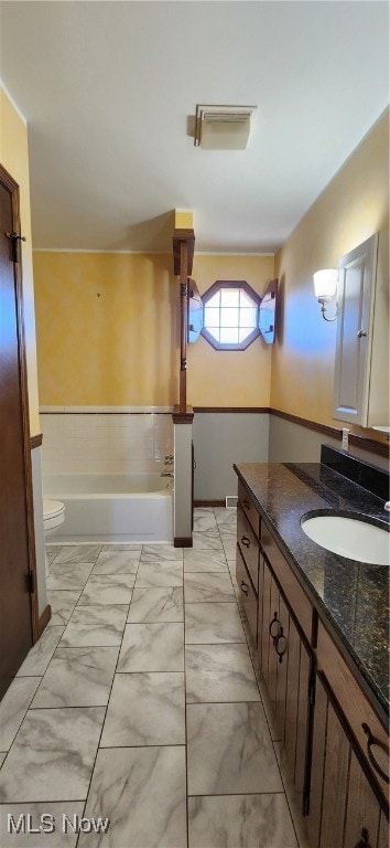 bathroom with a tub to relax in, vanity, and toilet