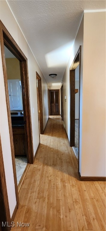 hallway featuring a textured ceiling and light wood-type flooring