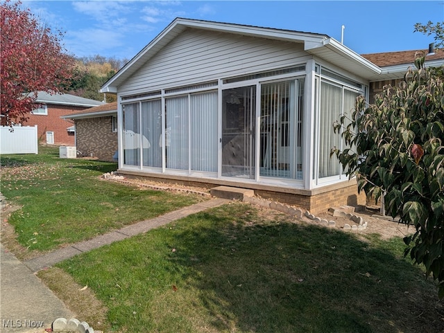 rear view of property featuring a sunroom and a lawn